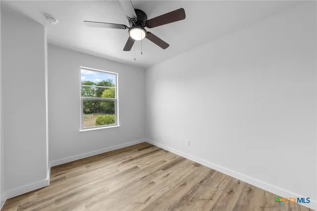 an empty room with a window and ceiling fan
