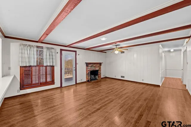 a large white kitchen with wooden floor and large windows
