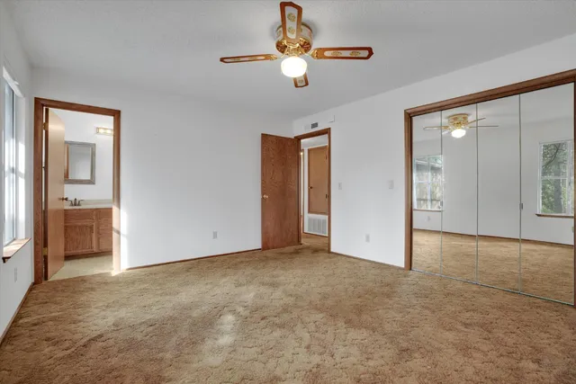 an empty room with closet and a chandelier fan