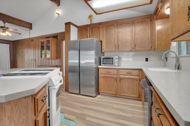 a kitchen with stainless steel appliances granite countertop a sink a stove a refrigerator cabinets and wooden floor