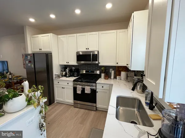 a view of kitchen sink a faucet potted plant and stove
