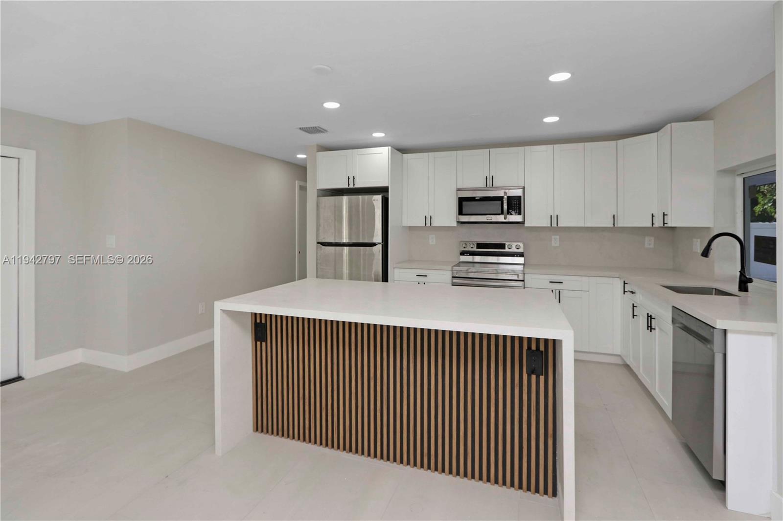 16232 Southwest 107th Court Miami, FL 33157 - Photo 6 of 32 a kitchen with kitchen island white cabinets and stainless steel appliances