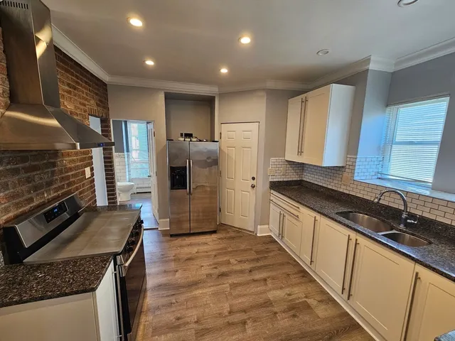 a view of a kitchen with stainless steel appliances granite countertop a sink and a stove