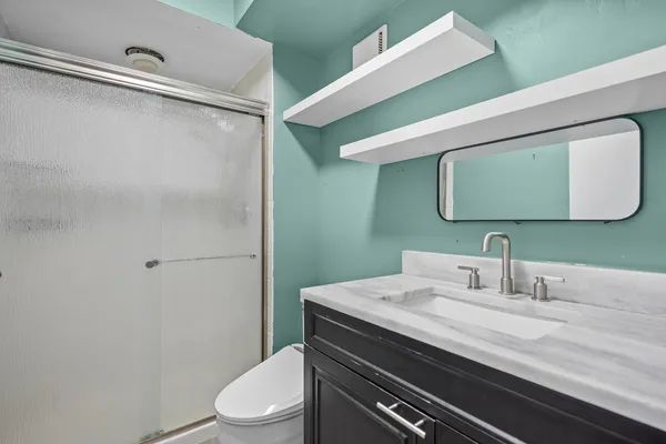 a bathroom with a granite countertop sink mirror vanity and toilet