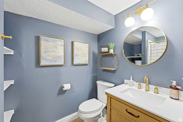 7935 Mustang Loop Road Park City, UT 84098 - Photo 33 of 60 Bathroom featuring a wood-finish vanity with a white countertop and integrated sink, gold-tone faucet, and a round mirror with a gold-tone frame