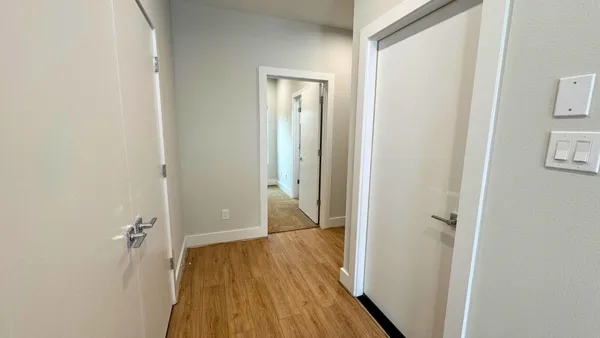 a view of a hallway with wooden floor and closet area