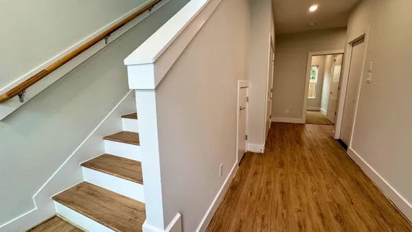 a view of a hallway with wooden floor and staircase
