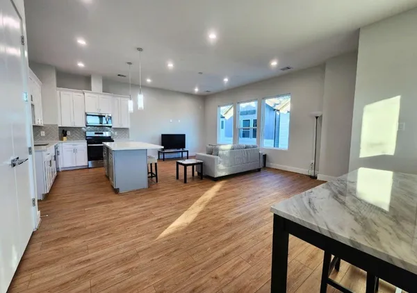 a living room with couches and kitchen view with wooden floor