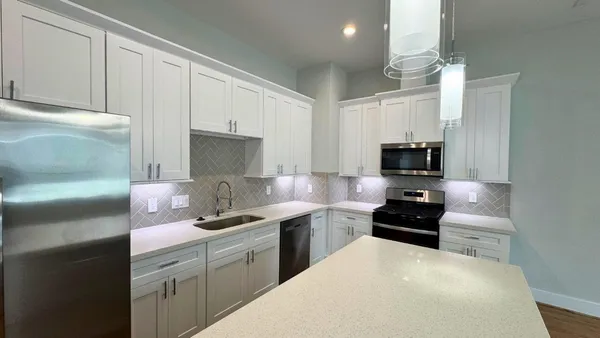 a kitchen with stainless steel appliances a sink a stove a microwave a sink a refrigerator and cabinets