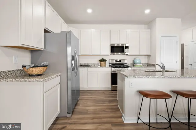 a kitchen with stainless steel appliances granite countertop a stove a sink a refrigerator and white cabinets