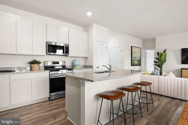 a kitchen with stainless steel appliances granite countertop a stove top oven a sink dishwasher and a refrigerator with wooden floor