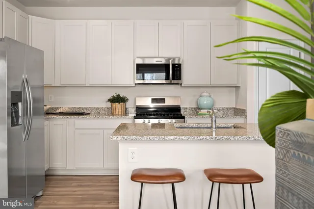 a kitchen with stainless steel appliances granite countertop a sink a refrigerator and a stove