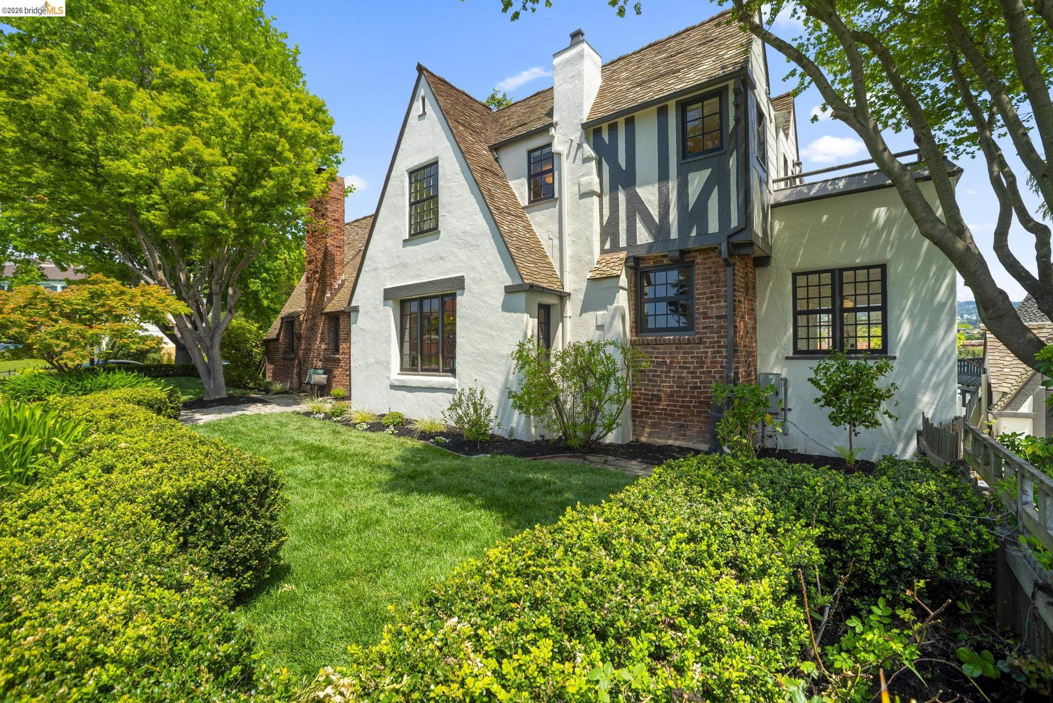 1087 Hubert Road Oakland, CA 94610 - Photo 60 of 67 Tudor-style residence featuring white stucco, dark timber framing, a multi-gabled roof, brick accents, and black-framed windows