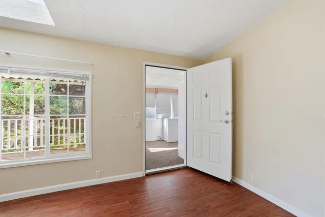 an empty room with wooden floor chandelier fan and windows