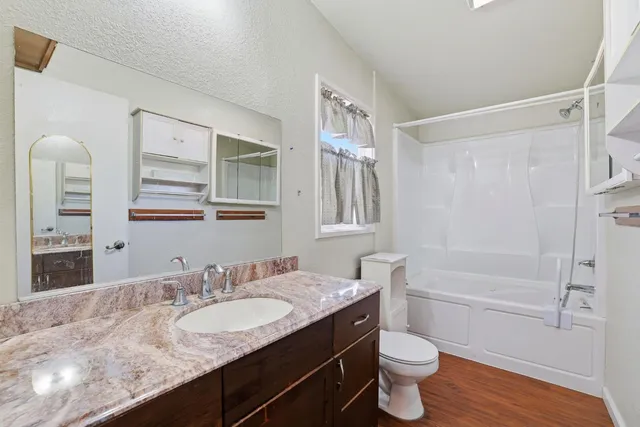 a backyard of a house with plants and large tree