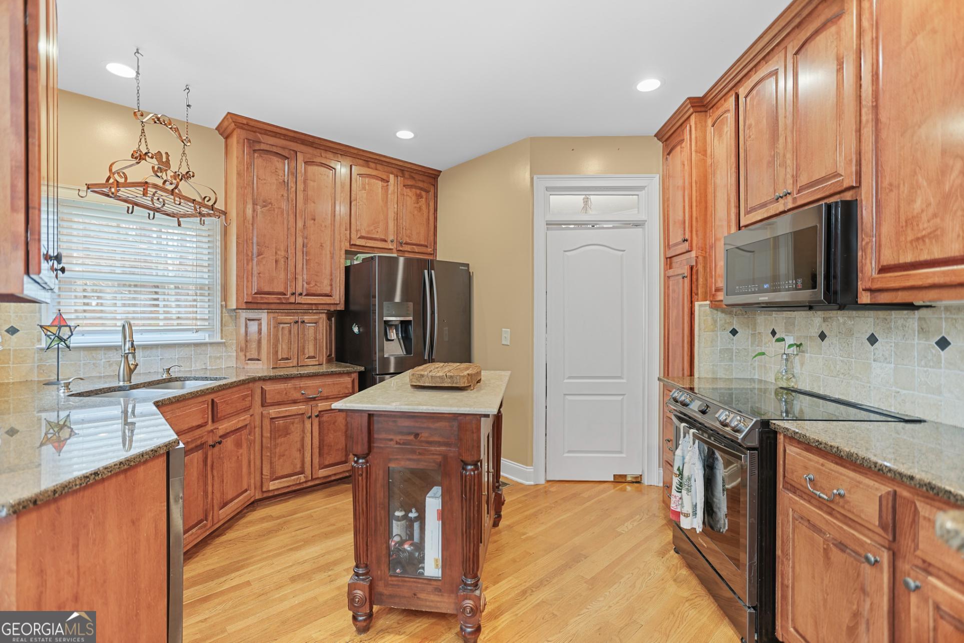643 Old Greenville Road Fayetteville, GA 30215 - Photo 24 of 59 a kitchen with stainless steel appliances granite countertop a refrigerator a stove top oven a sink dishwasher and wooden cabinets with wooden floor