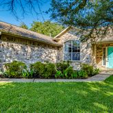 a view of a house with brick walls and a yard with plants