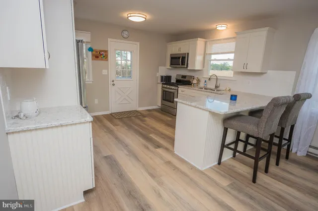 a kitchen with granite countertop white cabinets sink and stainless steel appliances