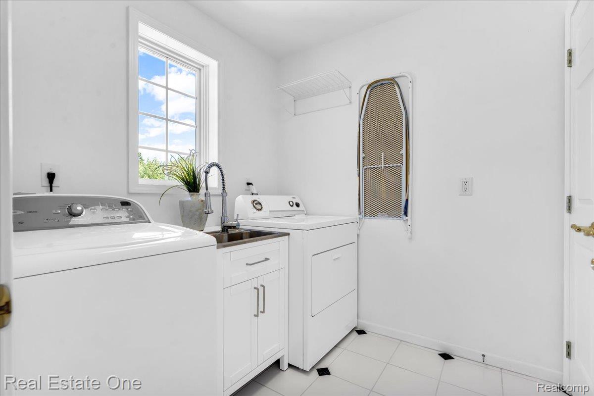 33850 Braebury Ridge Farmington, MI 48331 - Photo 36 of 85 Dedicated laundry room featuring a utility sink with a high-arc faucet, white cabinetry, a large window, and tiled flooring with accent squares
