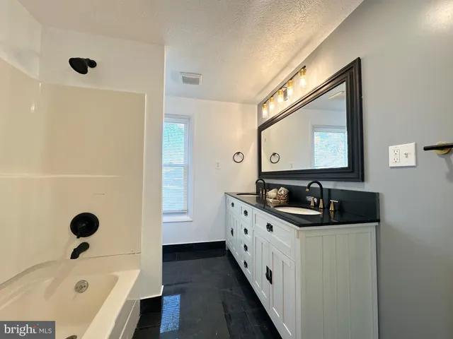 a bathroom with a tub sink and mirror