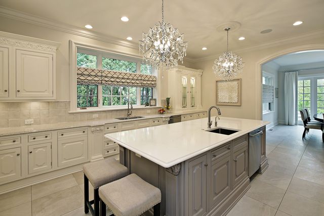 a large kitchen with a large counter top space a sink stainless steel appliances and cabinets