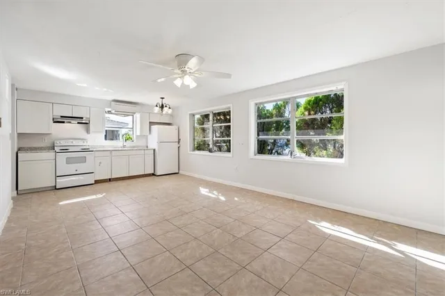 a large white kitchen with white cabinets and chandelier