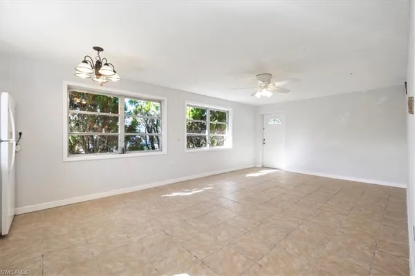 an empty room with windows and ceiling fan