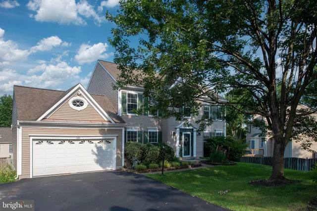 a view of a white house next to a yard with plants and trees