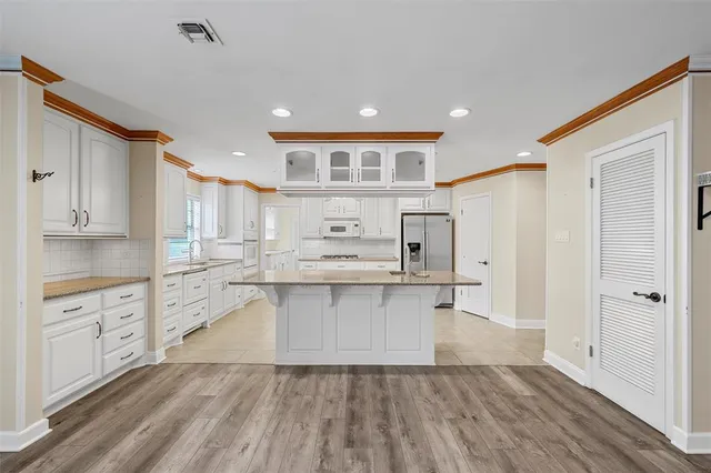 a large white kitchen with white cabinets and wooden floor