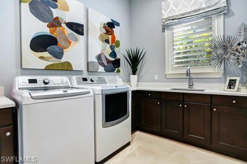 595 Regatta Road Naples, FL 34103 - Photo 34 of 40 Laundry area featuring built-in dark wood cabinetry, light-toned countertops, an undermount sink with a chrome faucet, and a window with blinds