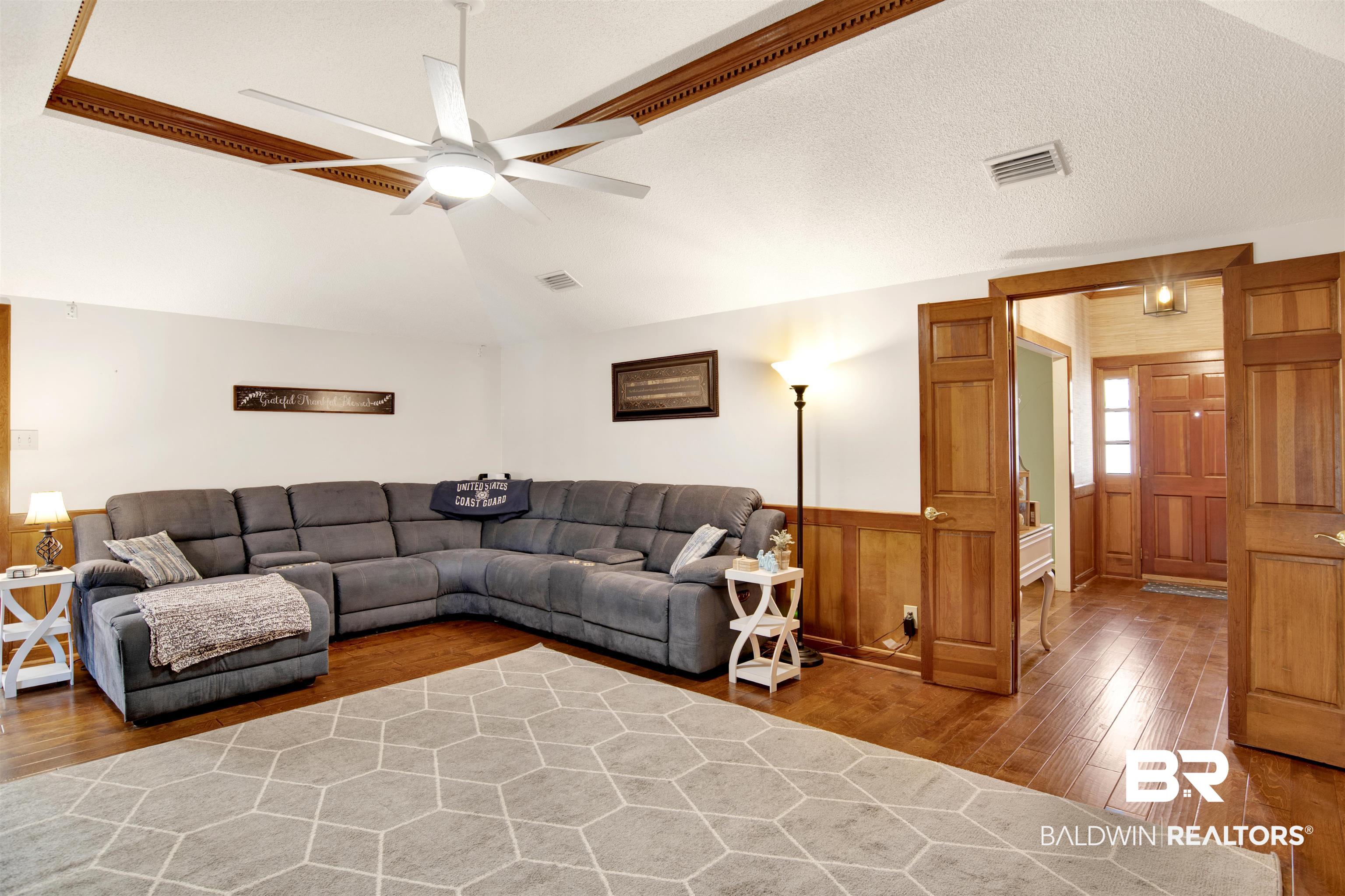 7431 Summer Court Mobile, AL 36695 - Photo 31 of 37 Living area with wood finished floors, ceiling fan, vaulted ceiling, wainscoting, and wooden walls