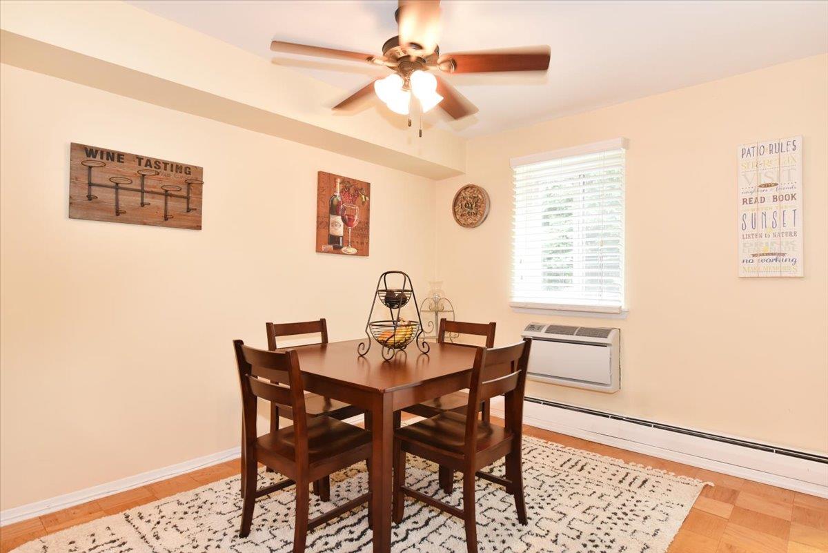 320 East Shore Road, Unit 10C Great Neck, NY 11023 - Photo 17 of 30 Dining space featuring a baseboard radiator, ceiling fan, and a wall mounted air conditioner