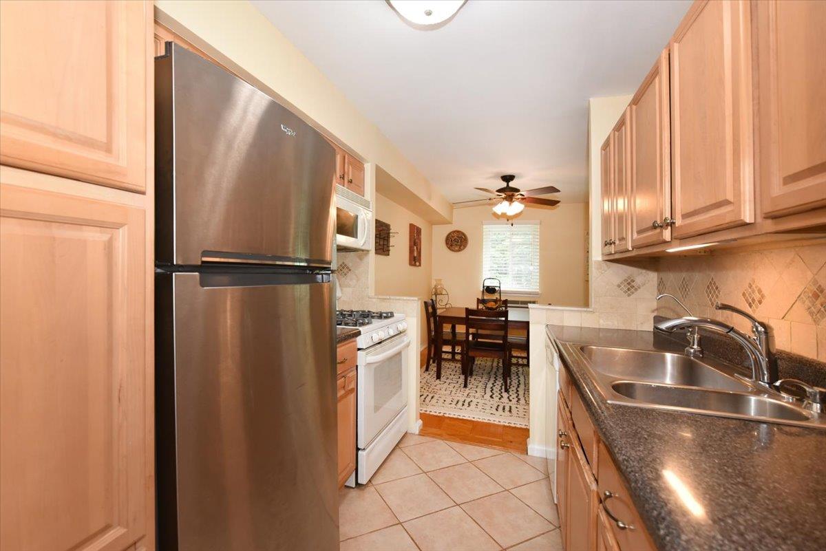 320 East Shore Road, Unit 10C Great Neck, NY 11023 - Photo 20 of 30 Kitchen with white appliances, decorative backsplash, light tile patterned floors, a ceiling fan, and light brown cabinets