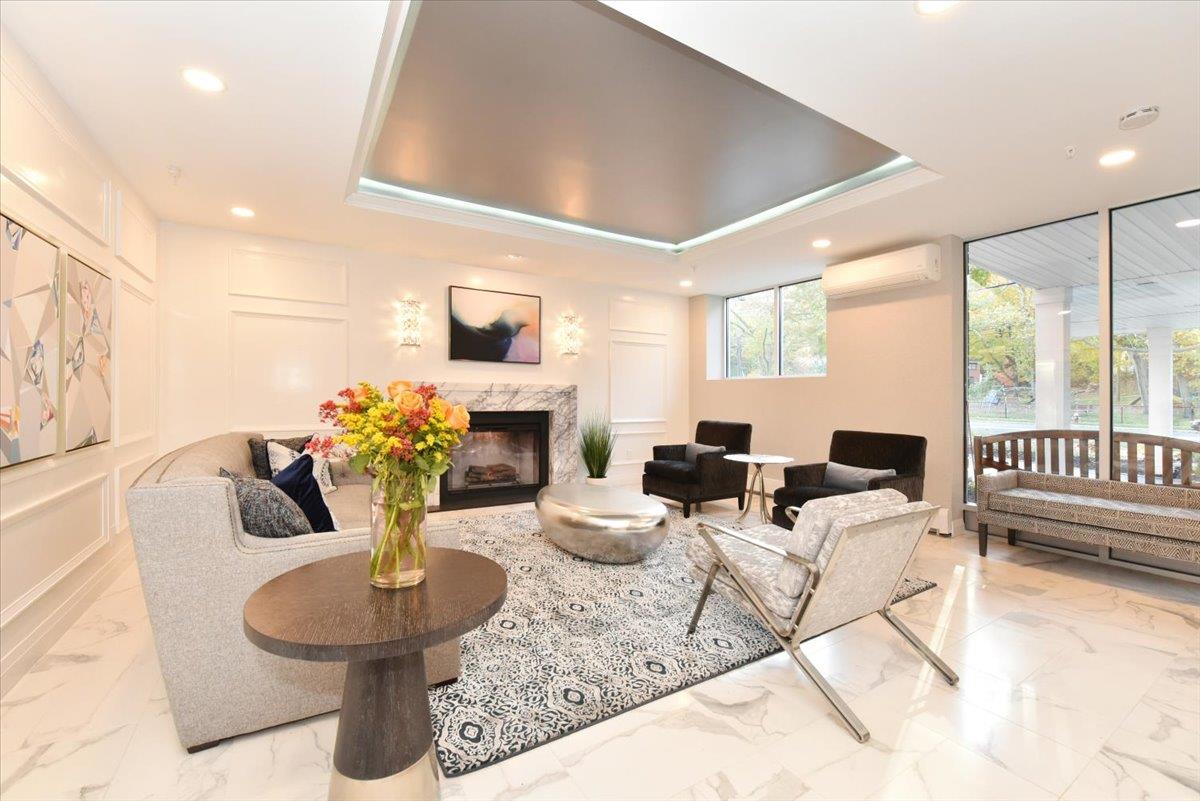 320 East Shore Road, Unit 10C Great Neck, NY 11023 - Photo 6 of 30 Living area with light marble finish floors, a wall mounted air conditioner, a high end fireplace, recessed lighting, and a tray ceiling