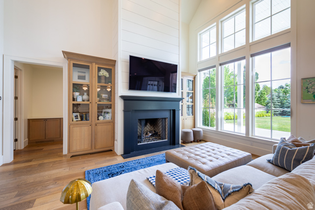 630 East Center Street Alpine, UT 84004 - Photo 38 of 115 Spacious living area featuring double-height ceilings with shiplap accents, wood-finish flooring, and a dark-toned fireplace with a built-in hearth