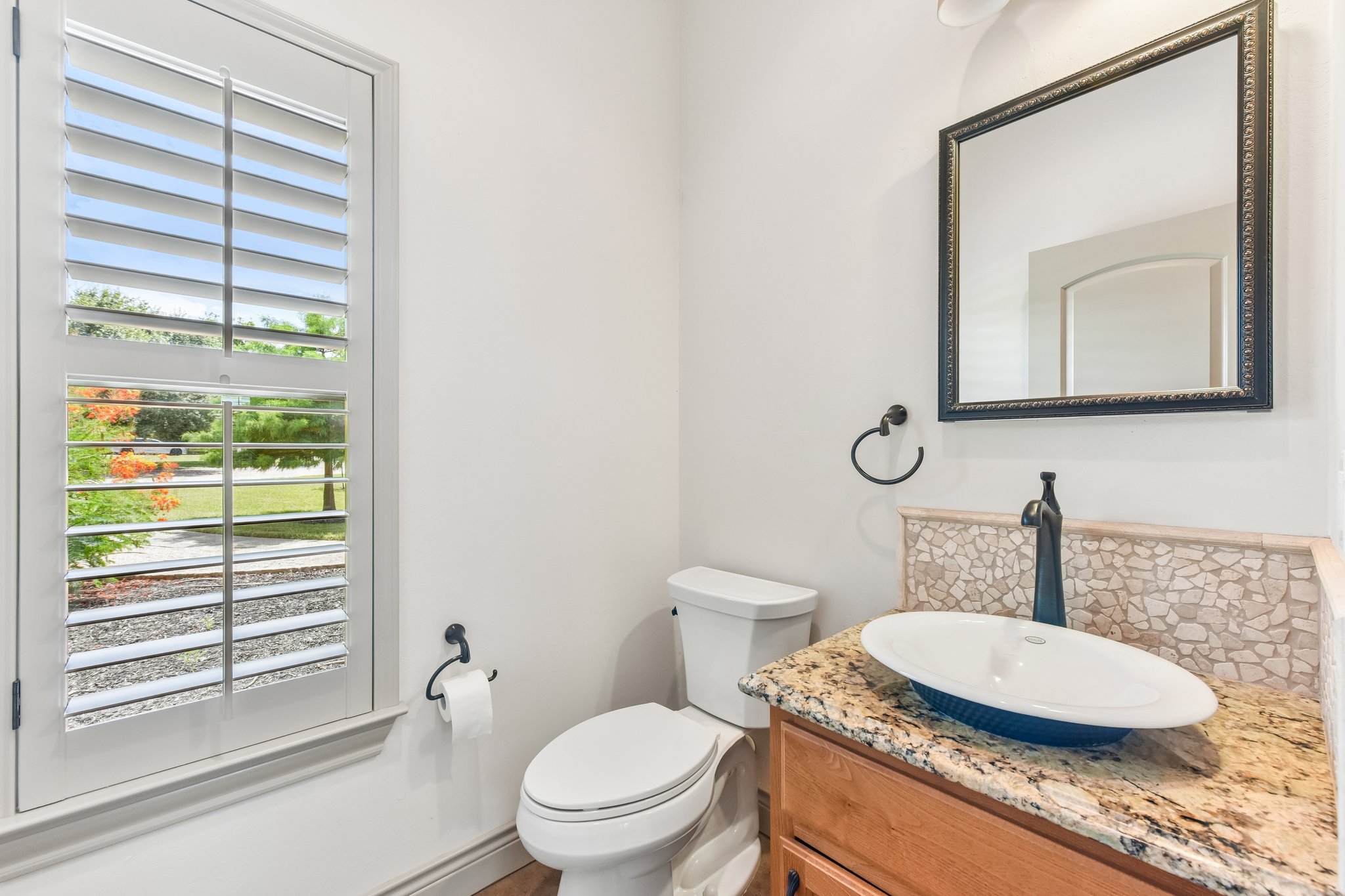 163 Powder Horn Road Bastrop, TX 78602 - Photo 16 of 34 Natural light filters through classic plantation shutters into a well-appointed powder room.
