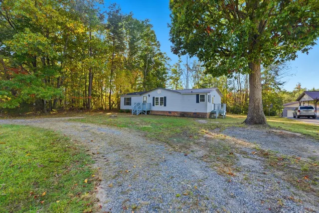 a view of a house with a yard and large trees