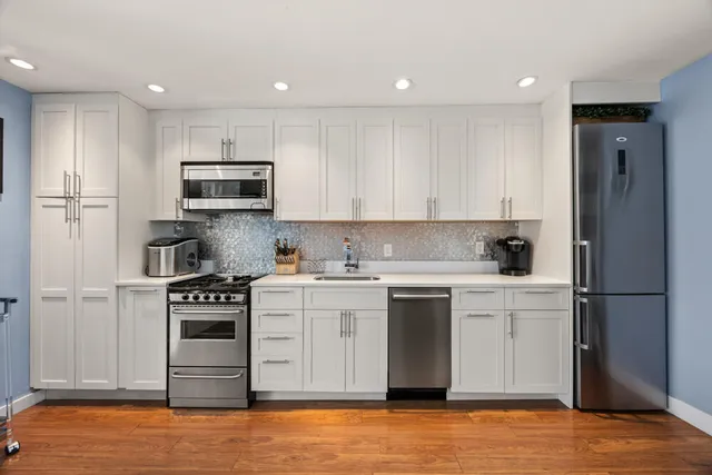 a kitchen with stainless steel appliances granite countertop a stove a sink and a refrigerator