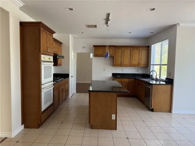 a kitchen with granite countertop a refrigerator and a stove top oven