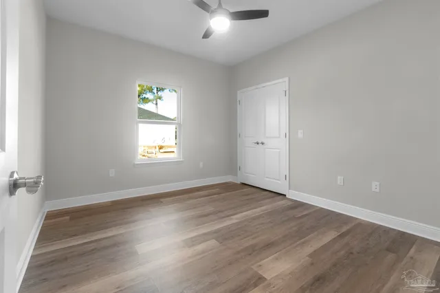 an empty room with wooden floor and windows