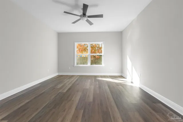 an empty room with wooden floor ceiling fan and windows
