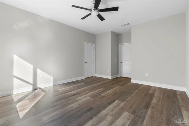a view of empty room with wooden floor and fan