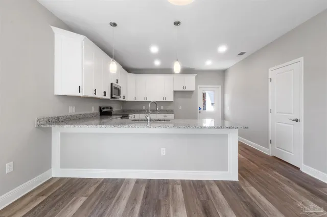 a view of kitchen with granite countertop stainless steel appliances stove sink and cabinets