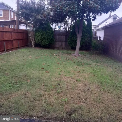 a view of a backyard with large trees and wooden fence
