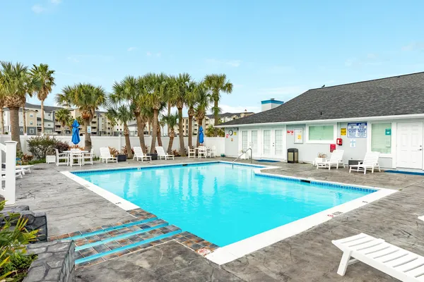 a view of swimming pool with outdoor seating and house in the background