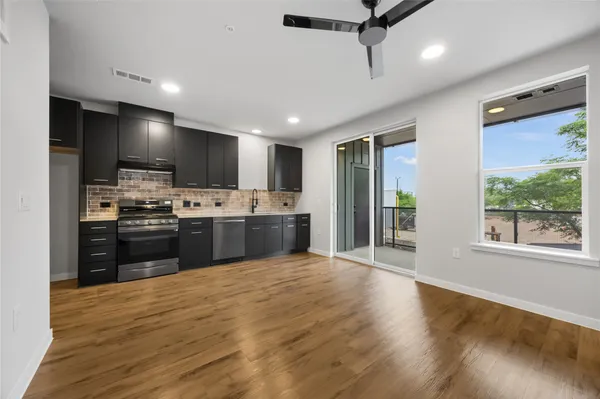 a kitchen with stainless steel appliances kitchen island granite countertop a refrigerator a sink dishwasher a stove and a microwave oven with wooden floor