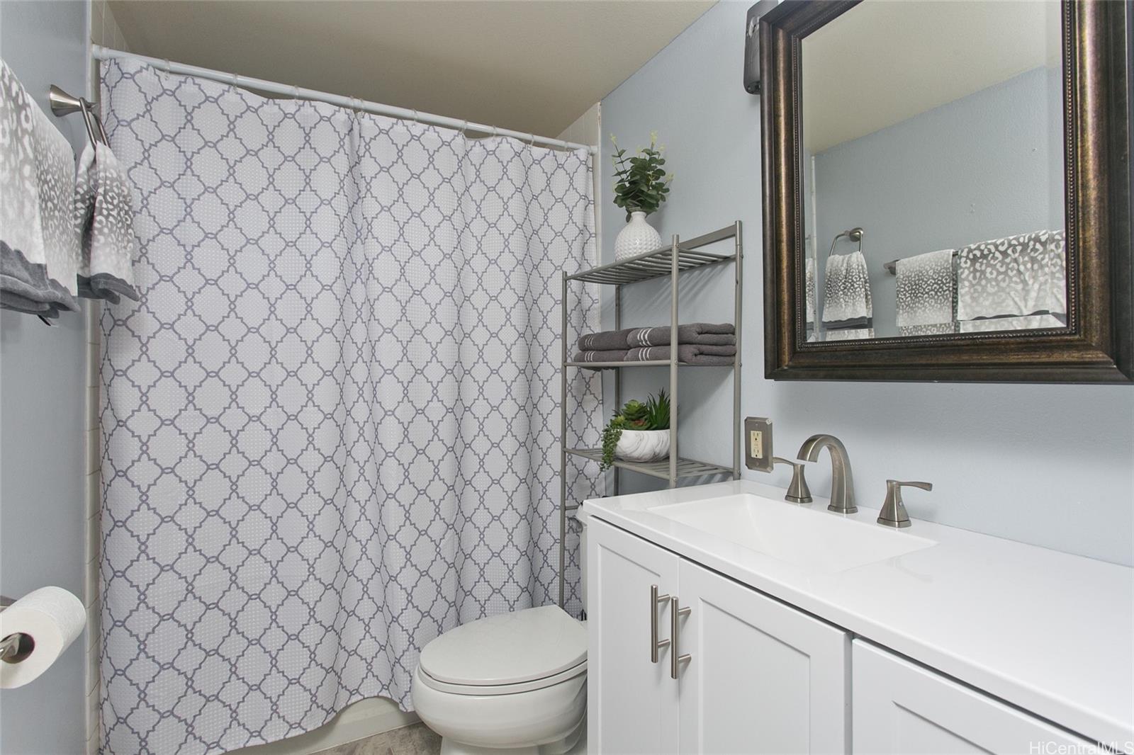94-302 Paiwa Street, Unit 202 Waipahu, HI 96797 - Photo 8 of 12 a bathroom with a sink a toilet and shower curtain
