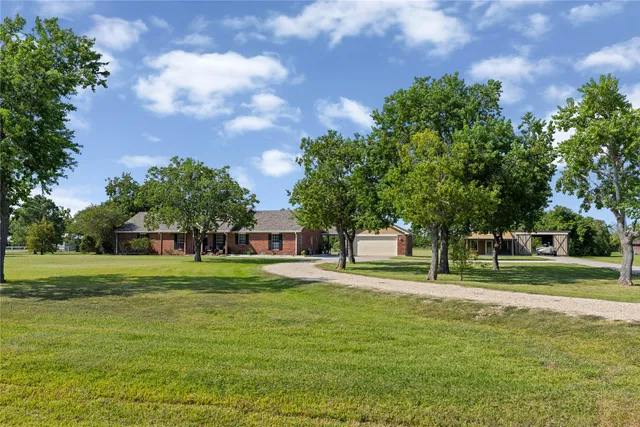 a house view with a big yard and large trees