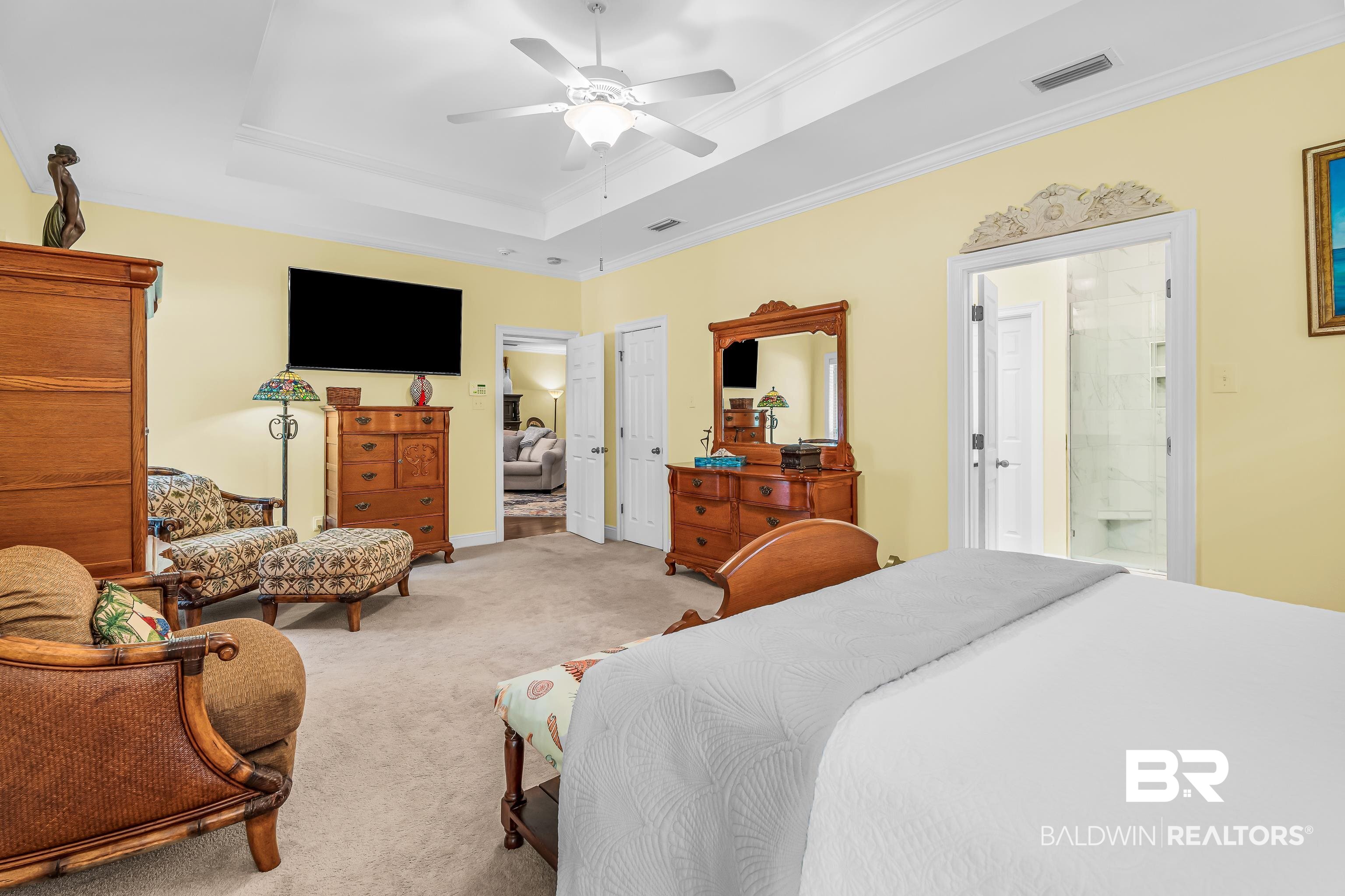 7014 Blakeley Road Daphne, AL 36527 - Photo 35 of 45 Spacious interior room featuring a tray ceiling with a ceiling fan, light-toned carpeting, and a doorway leading to a bathroom with a tiled shower