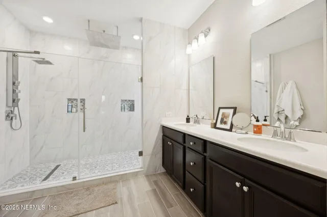 a bathroom with a double vanity sink mirror and shower